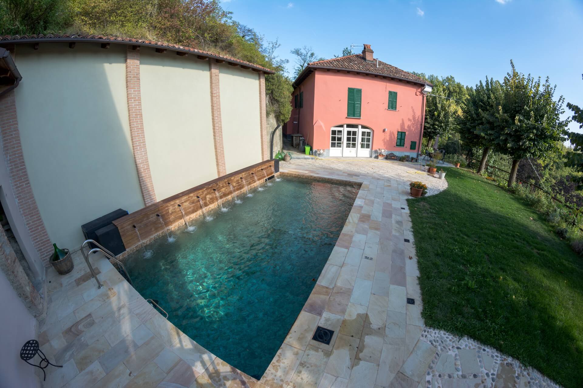 Piscina interrata con gioco d’acqua e rivestimento effetto pietra